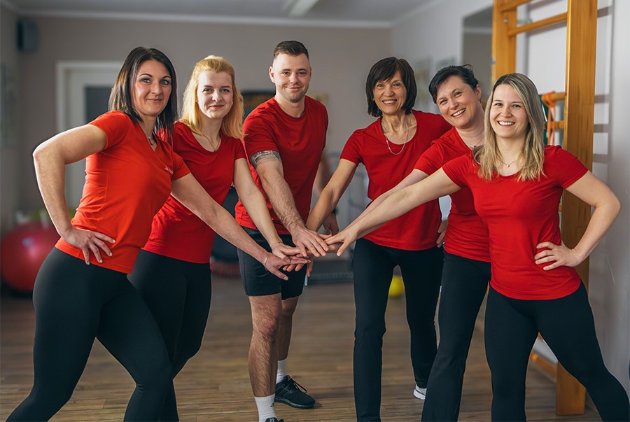 Das Physiotherapie-Team von Physiotherapie Beyer in Schmölln-Putzkau – sechs Therapeutinnen und Therapeuten in roten Shirts im Behandlungsraum