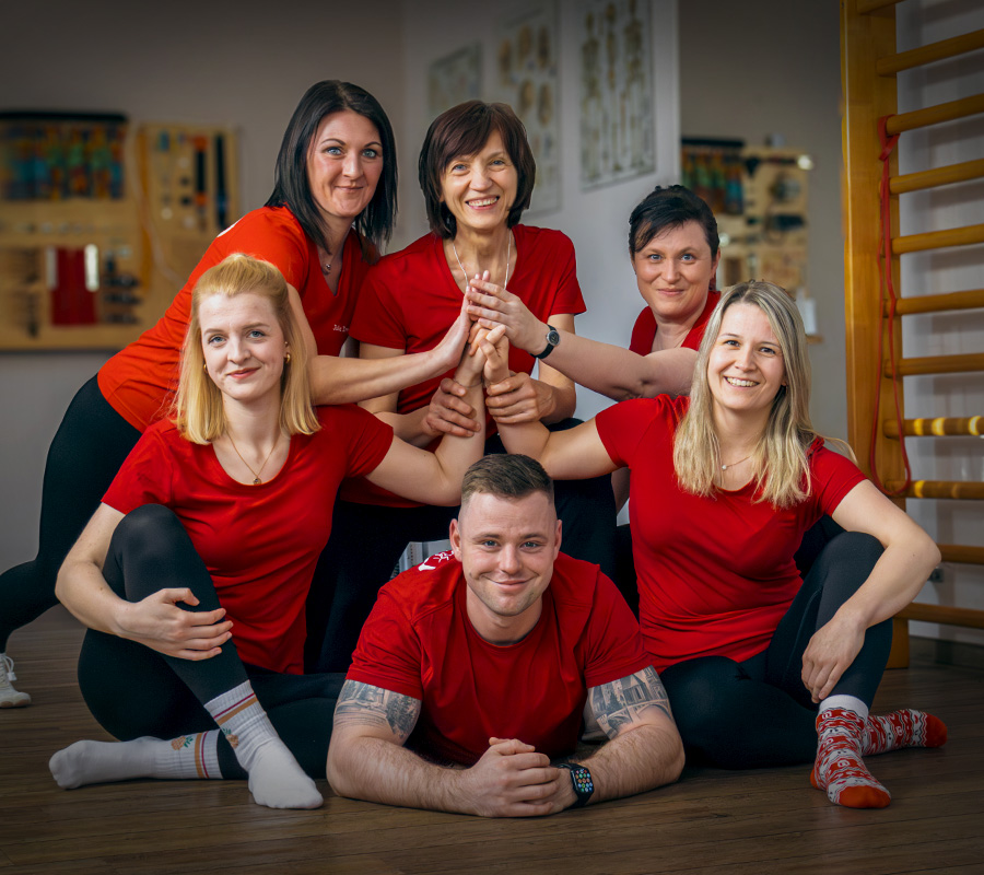 Team der Physiotherapie Beyer in Schmölln-Putzkau – fünf Physiotherapeutinnen und ein Physiotherapeut in roten Shirts im Sportraum